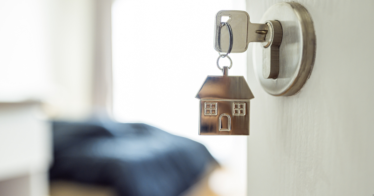 NDIS Rental Properties - A Key is inserted in a lock of a door and the key has a small ring of small house