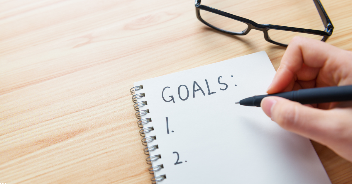 SMSF Property Investment - A Person is writing goals on a paper and there's a spectacles