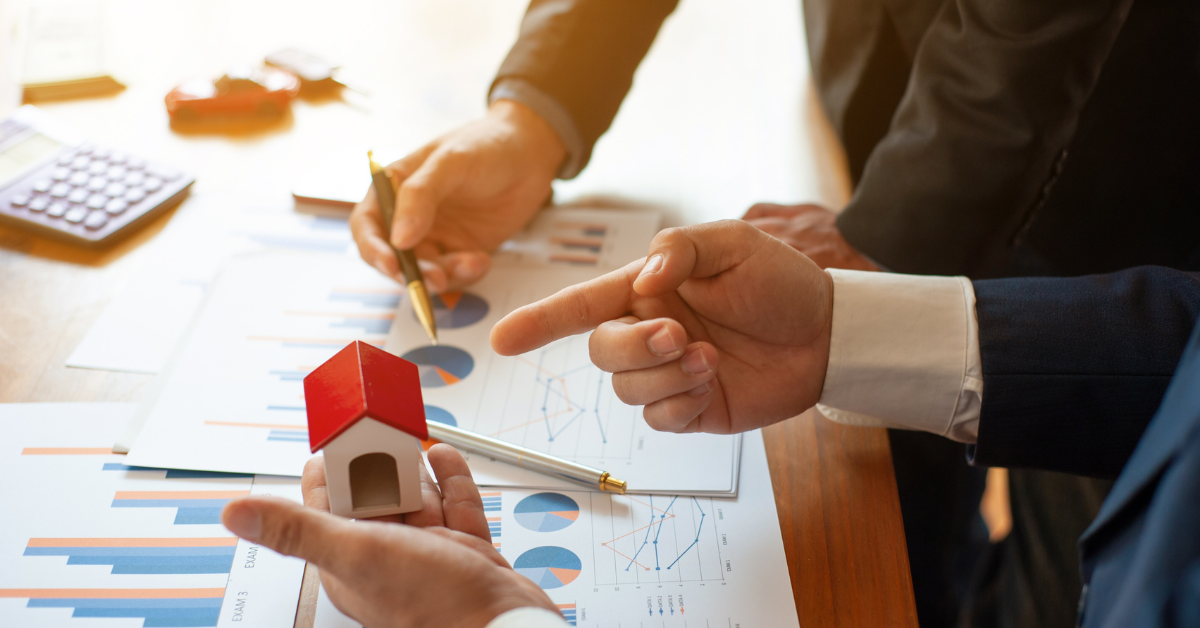 Off Market Properties - Man holding a dummy small house and another man is pointing at analytical data using a pen