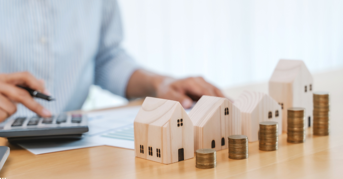 SMSF Property Featured Image - A Man Sitting on a table calculating something and there are dummy houses and coins as well in the table indicating investing in properties makes profits and secures a better future