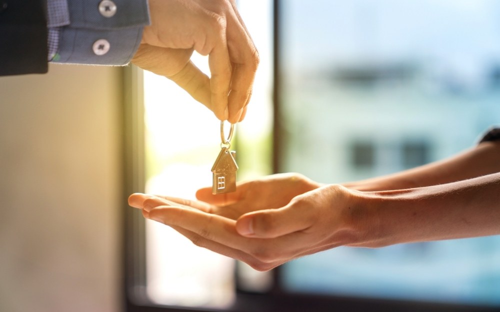 a broker is handing over a investment property to a first time home buyer