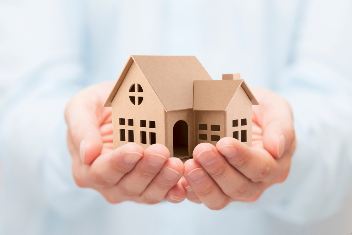 A person holding a dummy house within his hands